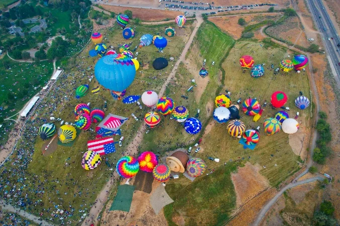 Hot air balloon festival Aerial view of colourful hot air balloons on a grassy field during an event.