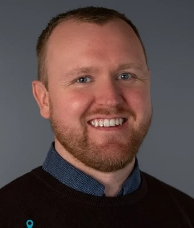 Matt, the Founder of CDIM Smiling man with short hair wearing a dark sweater over a collared shirt.