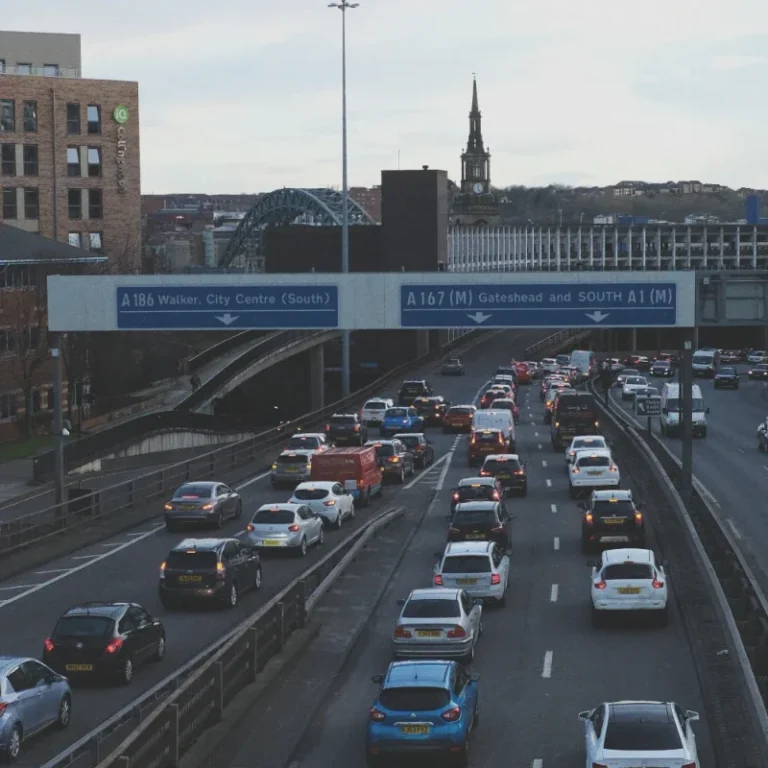 Busy motorway with traffic and city buildings in the background, including a church spire.
